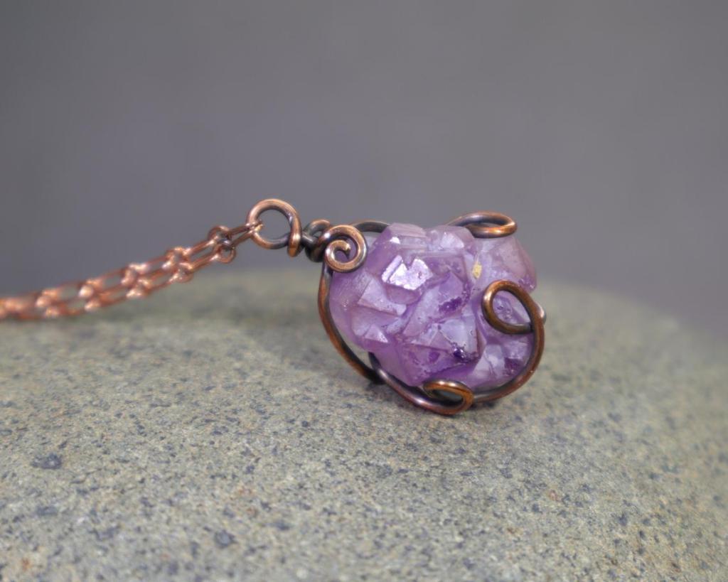 rustic elestial amethyst pendant wire wrapped in copper sitting on a rock