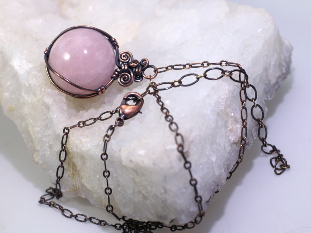 Rose Quartz Sphere wire wrapped with copper wire hanging from a copper flat link chain with a lobster clasp and an extender chain