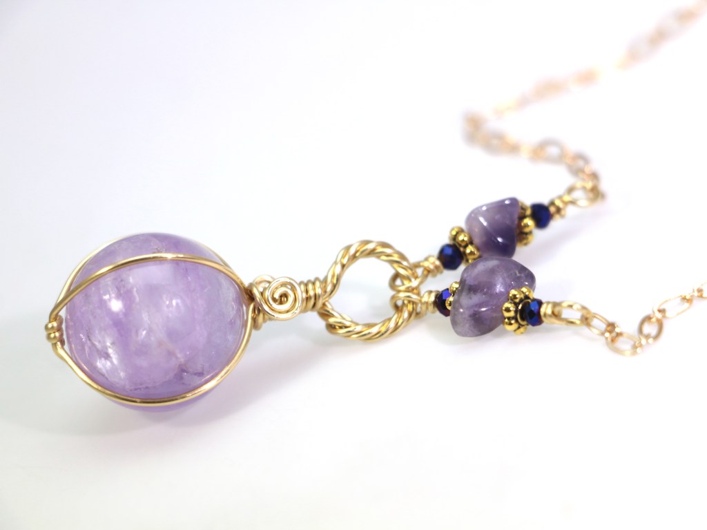 Lavender amethyst crystal ball wire-wrapped with golden jeweler's brass and hung with matching amethyst chip bead links from a sold plated brass flat linked cable chain