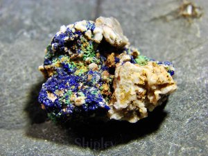 Raw azurite specimen with deep blue crystal formations and green malachite on natural rock matrix.