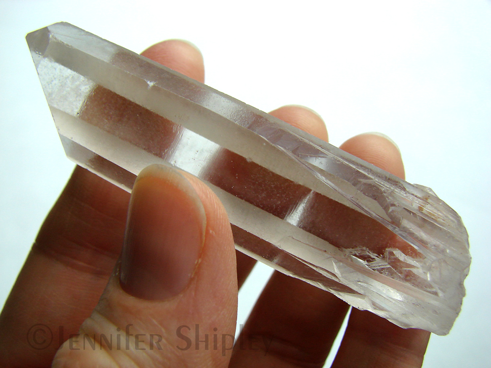 A clear quartz crystal with showing the typical hexagonal (six-sided) prisms terminated with a six-sided pyramid. M-faces are the long straight roughly parallel sides leading to the termination (point.)